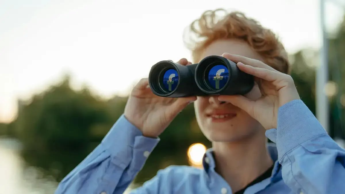 Person schaut durch Fernglas mit Facebook-Logo-Gläsern