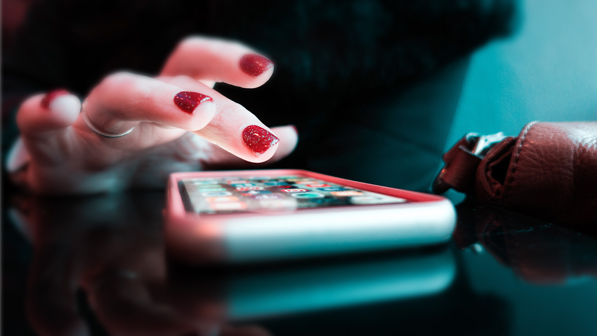 rot lackierte Fingernägel tippen auf Smartphone