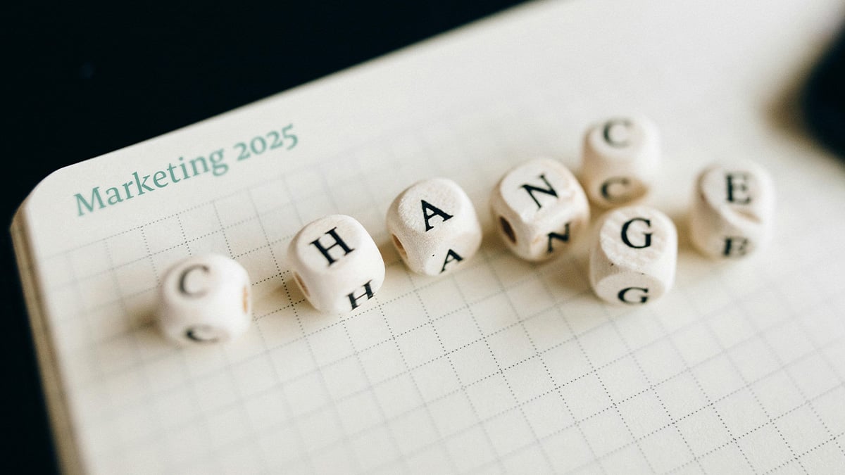 Auf einem Notizheft mit der Überschrift "Marketing 2025" sind Würfel mit Buchstaben die wahlweise CHANGE oder CHANCE ergeben